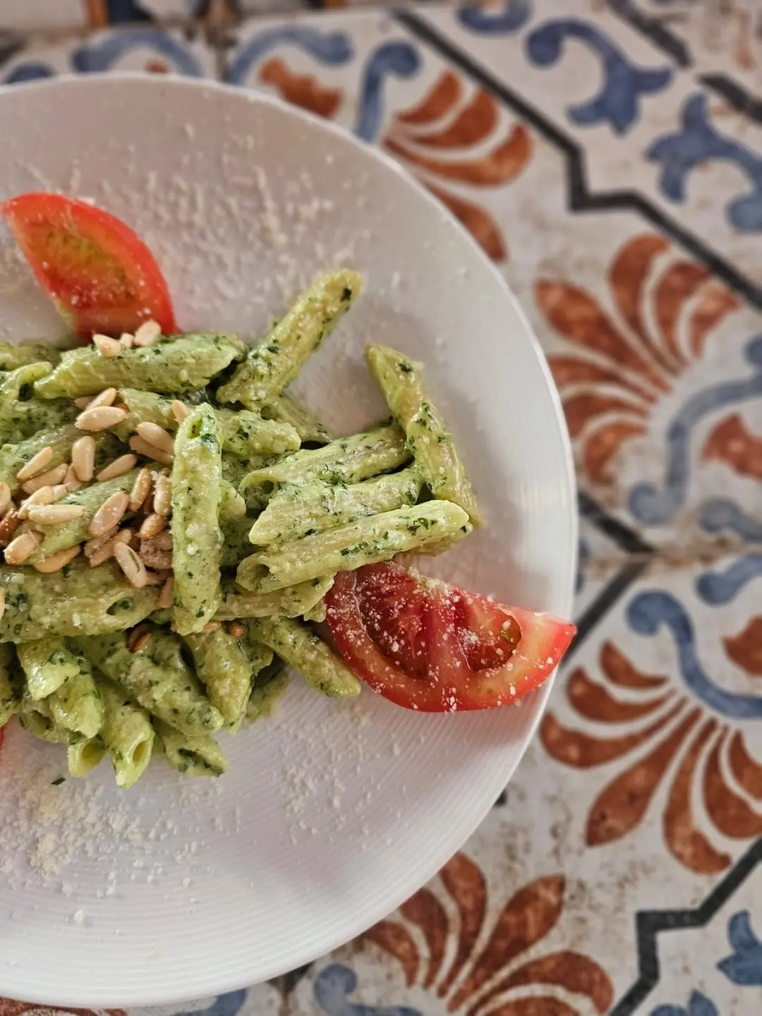 Penne pasta tossed with basil pesto, pine nuts and tomato