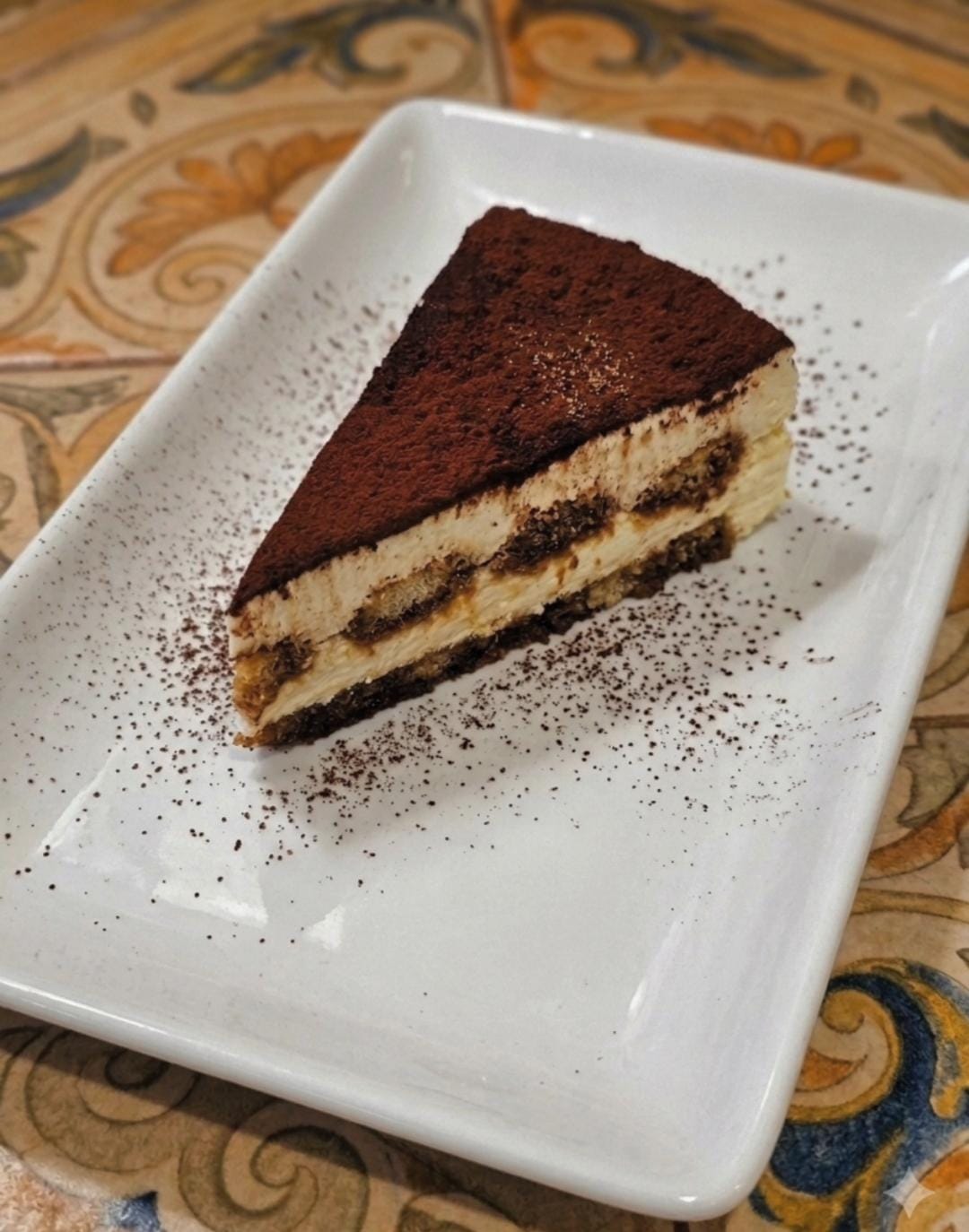 A slice of layered tiramisu dusted with cocoa